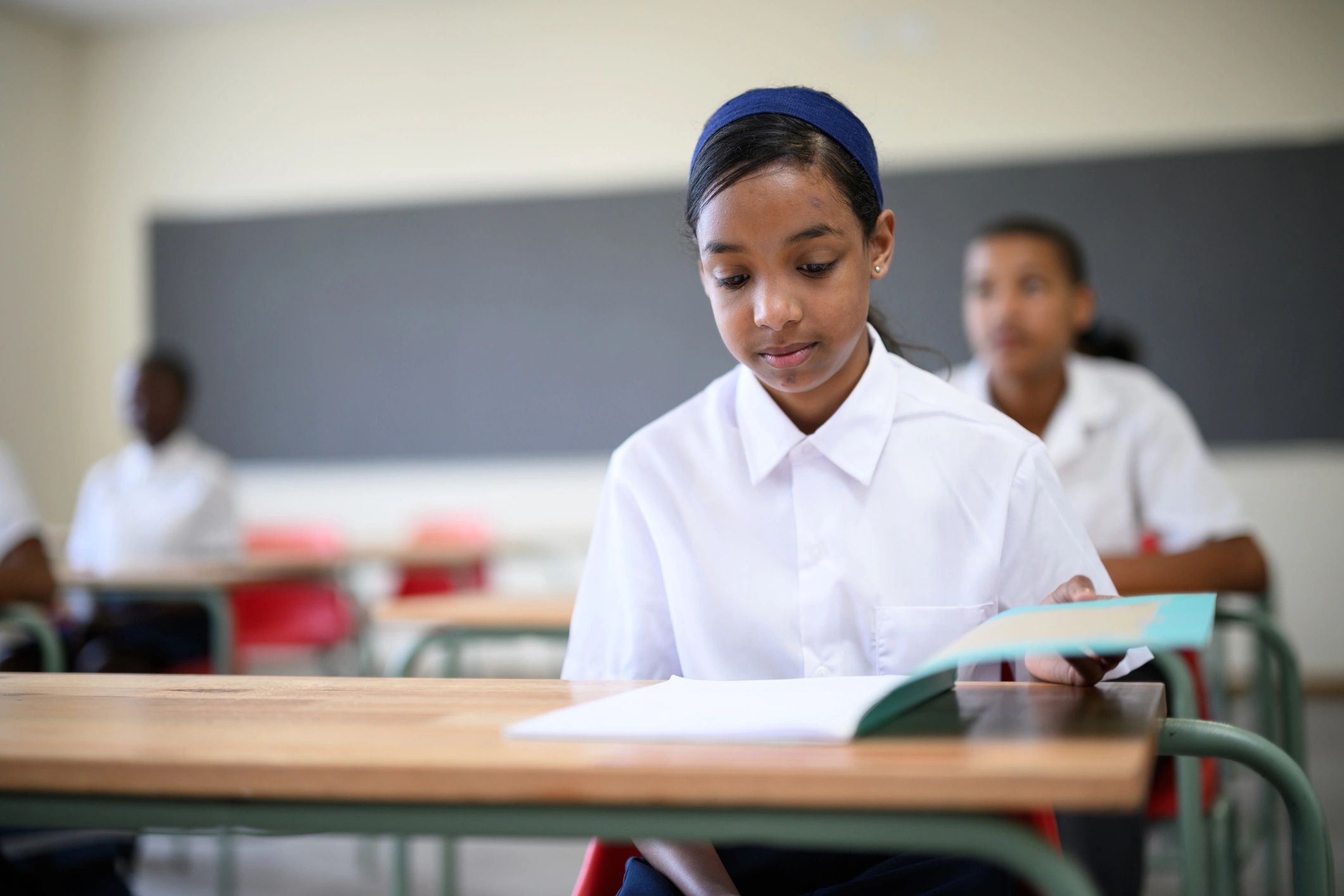 Student opening a schoolbook in classroom